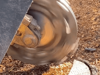 stump grinding machine blade hovering over tree stump